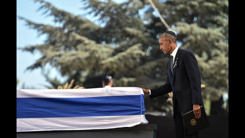 Obama touches Peres' coffin after speaking at the funeral.