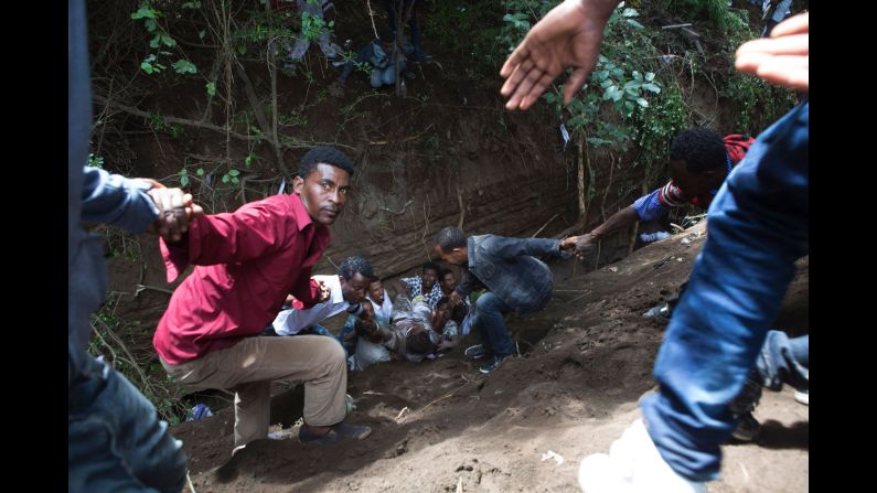 Bystanders work to remove an injured man from a ditch.