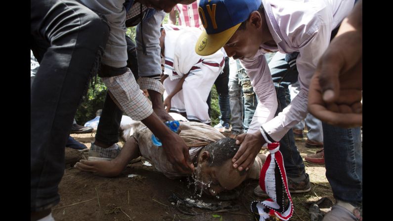 People help a man wash his eyes after police used teargas on festival participants.