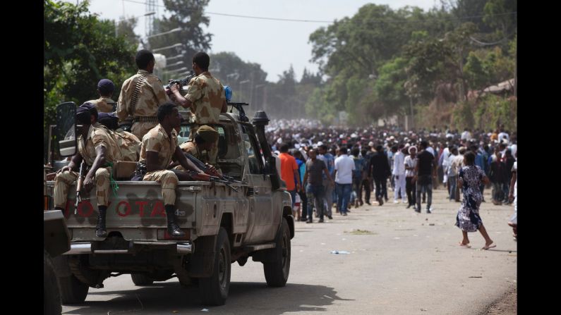 Oromo regional police officers wait in a pickup near a crowd of festival attendees.