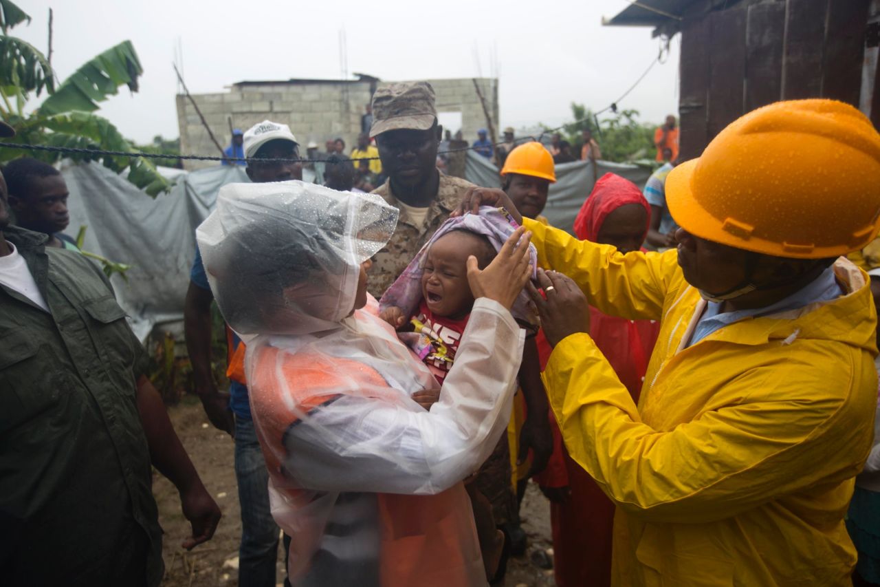Nice Simon, the mayor of Tabarre, Haiti, holds a baby as she helps evacuate the area along a river.