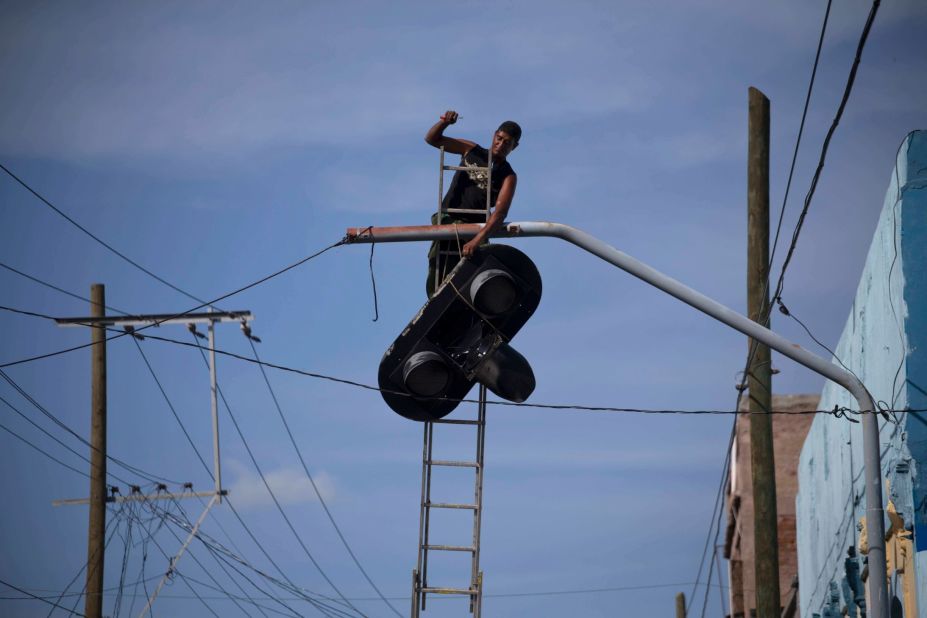 A worker dismantles a traffic light in Santiago before Hurricane Matthew struck Cuba.