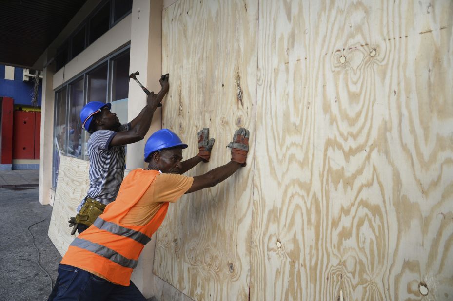 A worker nails a board to a storefront window in Kingston on Saturday, October 1.