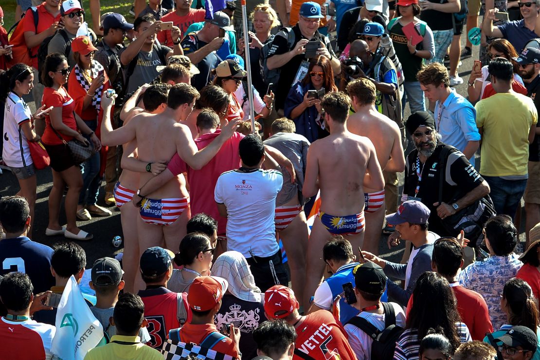 This picture taken on October 2, 2016, shows spectators with swimwear bearing a Malaysian flag posing for pictures during the Formula One Malaysian Grand Prix in Sepang. 
