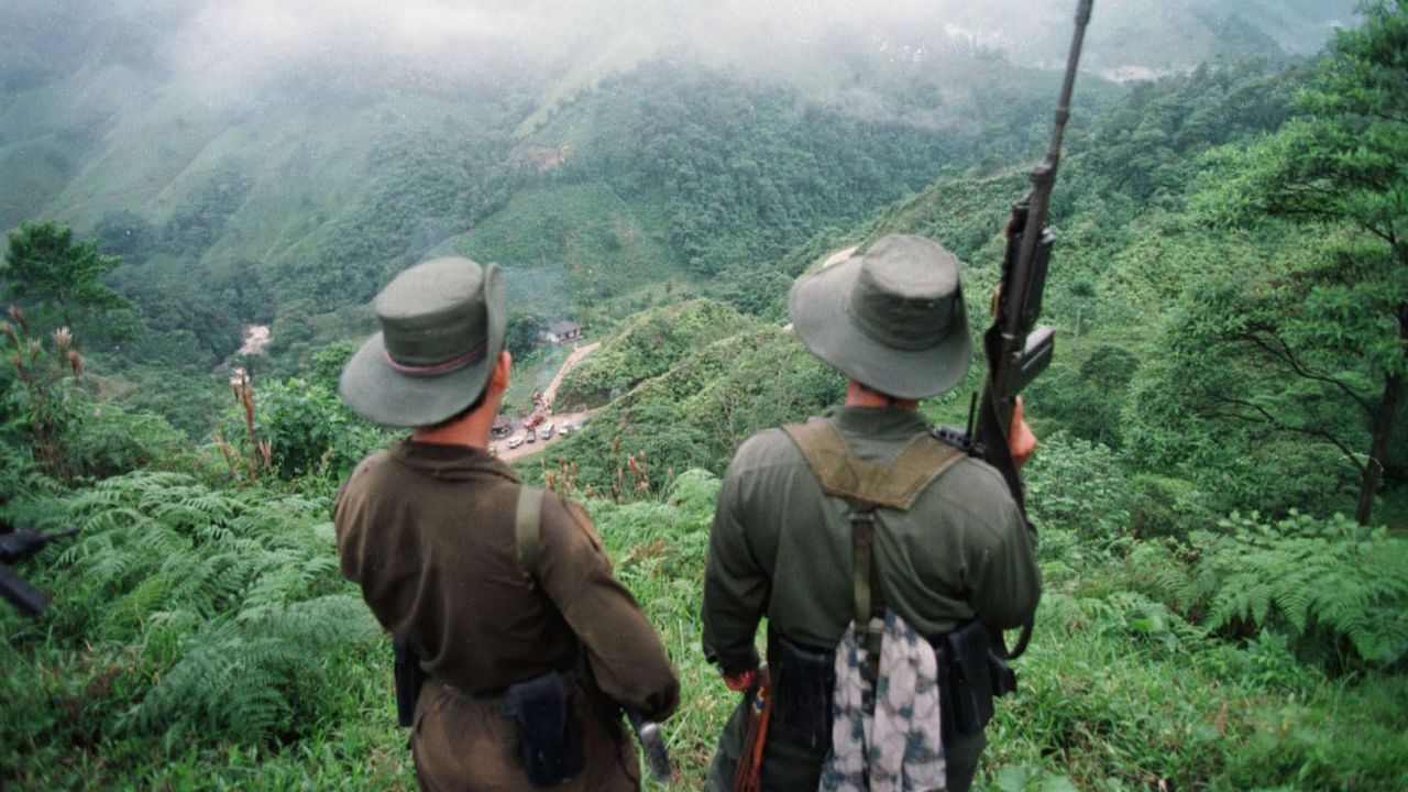 FLORENCIA, COLOMBIA:  Two armed soldiers belonging to the Revolutionry Armed Forces of Colombia (FARC) monitor the Berlin pass, 07 March, near Florencia, in the  southern Caqueta province of Colombia, where cars are prevented from going through after the rebels decreed 06 March a ban on "travel on roads and waterways for six days". The rebels try to dissuade voters from casting their ballots in the 08 March elections for congress. According to the rebels, the elections 08 March are illegitimate because the left has been forced out of national politics, following the murder over the past years of thousands of Colombia's left-wing politicians and supporters. AFP PHOTO PEDRO UGARTE (Photo credit should read PEDRO UGARTE/AFP/Getty Images)