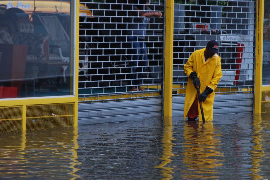 A worker clears a sewer on a flooded street in Santo Domingo.