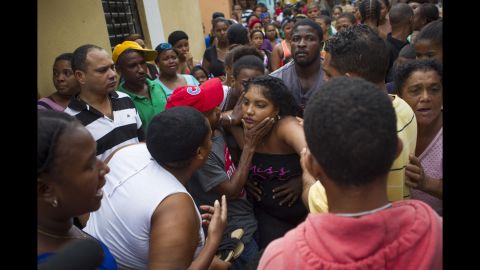 The mother of two girls who died in the storm is comforted near her home in Santo Domingo, Dominican Republic, on October 4. The girls were killed when a landslide caused by flooding breached the walls of their house.