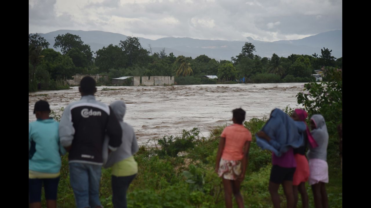 People observe the flooding of a river near Port-au-Prince on October 4.