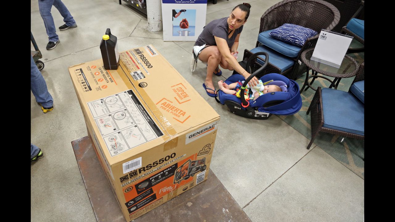 Anita Baranyi feeds her baby while keeping an eye on the generator she intends to purchase from a home-improvement store in Oakland Park, Florida, on October 4.