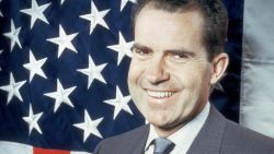 1960:  Republican presidential candidate Vice-President Richard Nixon (1913 -1994) laughing as he poses in front of the stars and stripes.  (Photo by Keystone/Getty Images)
