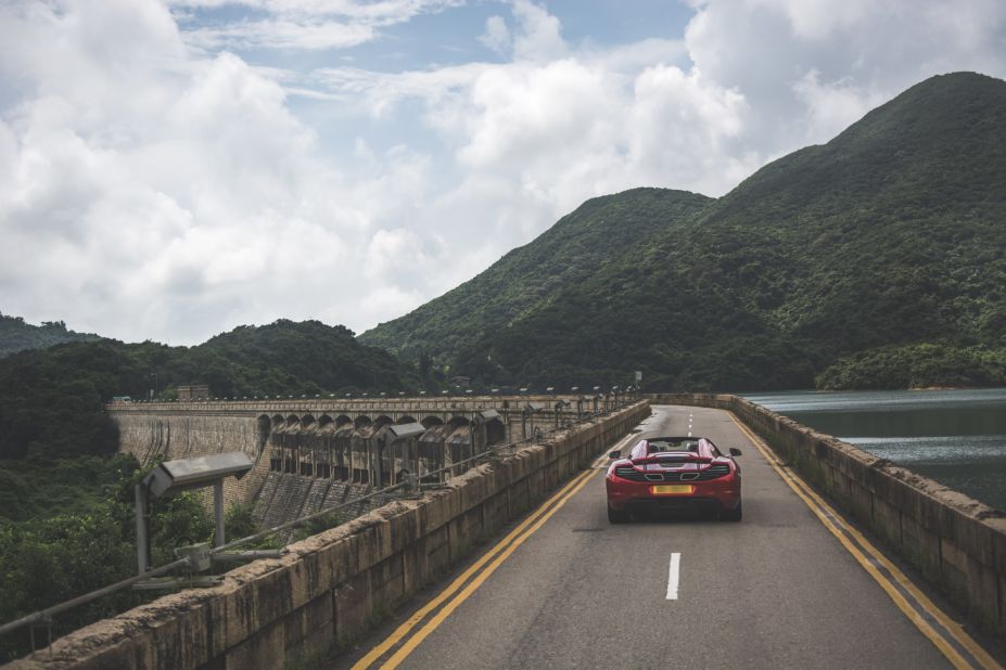 A narrow road crosses Tai Tam Tuk dam, which leads into Shek O Road's lush hills and beautiful coastal views.