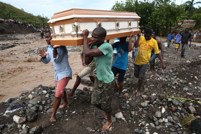 People carry a coffin and try to cross the La Digue river on October 5 after a bridge collapsed in Petit-Goave, Haiti.