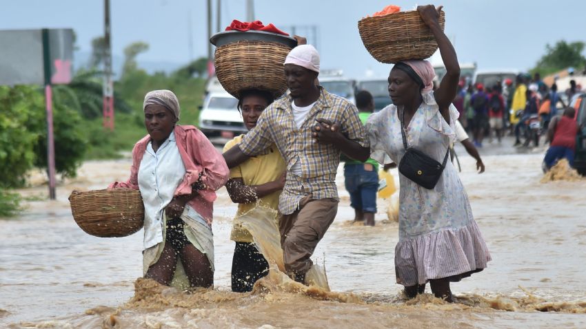 People try to cross the over flowing Rouyonne river in the commune of Leogane, south of Port-au-Prince, October 5.