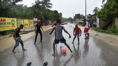 A group of young men play football in the rain on the roat to Leogane, as the hurricane passes.