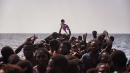 A child is lifted above a crowded boat as migrants wait to be rescued last month.