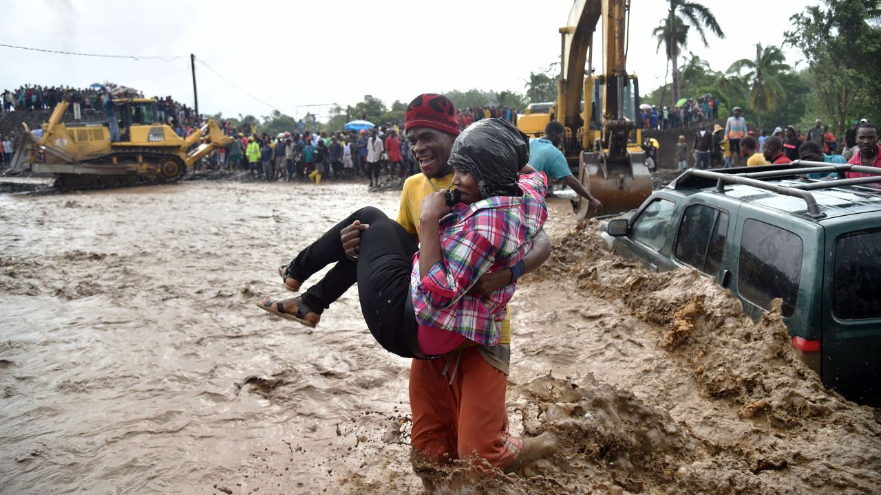A woman is carried across the river La Digue in Petit Goave where a bridge collapsed during the torrential rains.