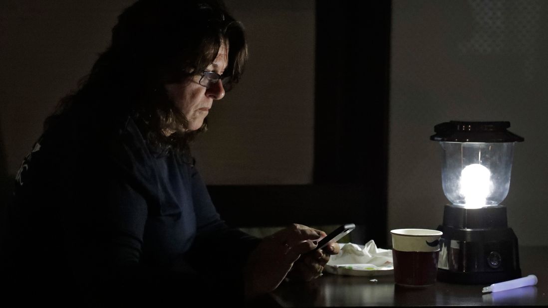 A woman uses her phone under a battery-operated lantern at a hotel in Titusville, Florida, on October 7.