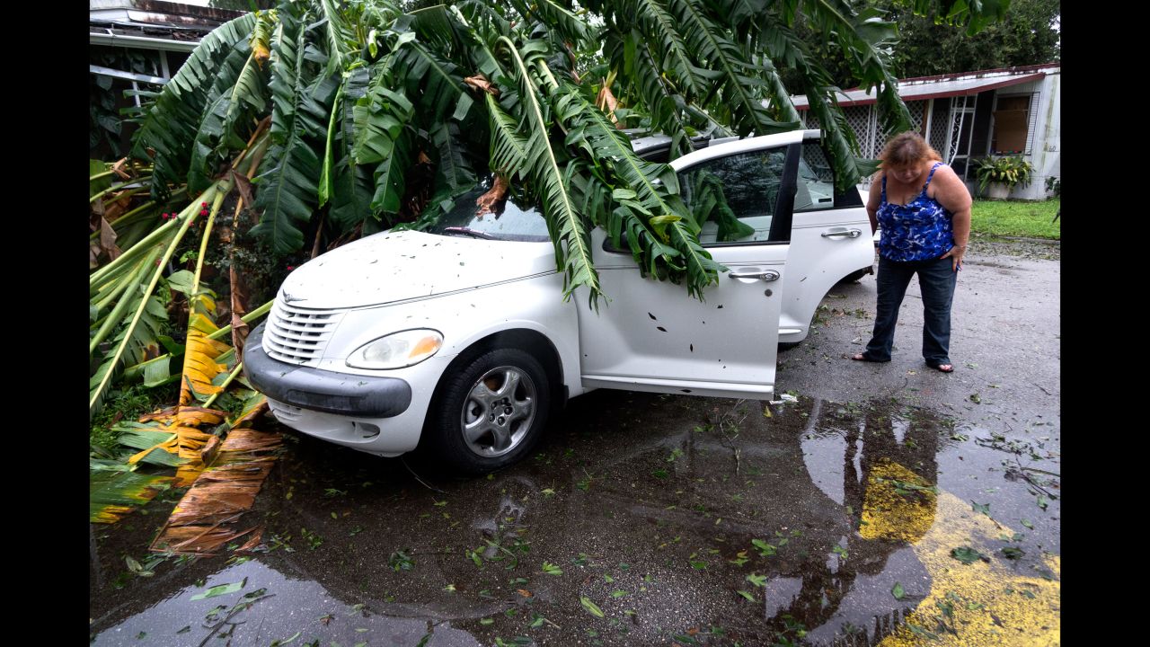 A woman inspects her damaged car under a tree in Fort Pierce, Florida, on October 7.