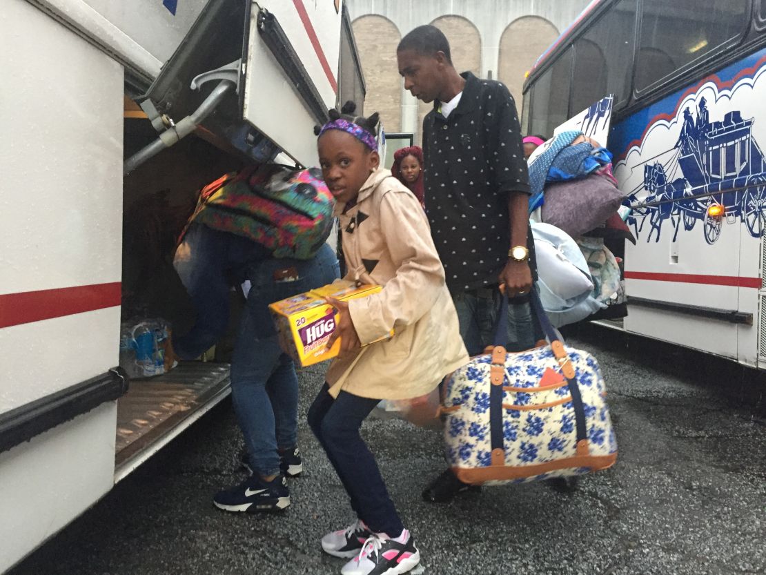 Families pack belongings onto a bus to evacuate. 