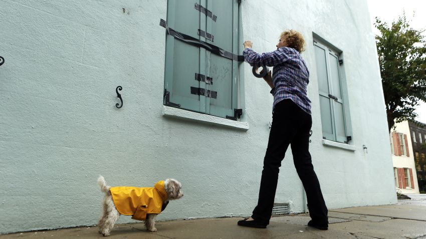 Barbara Hearst tapes closed the storm shutters on the windows to her home with her dog, Bandit, nearby ahead of Hurricane Matthew on October 7 in Charleston, South Carolina.