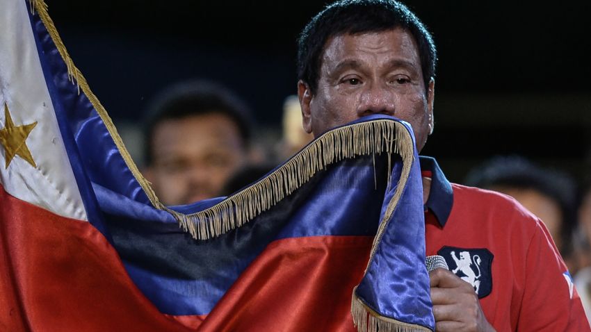 Presidential candidate and Davao Mayor Rodrigo Duterte kisses his national flag as he addresses his supporters during an election campaign rally ahead of the presidential and vice presidential elections in Manila on May 7, 2016.