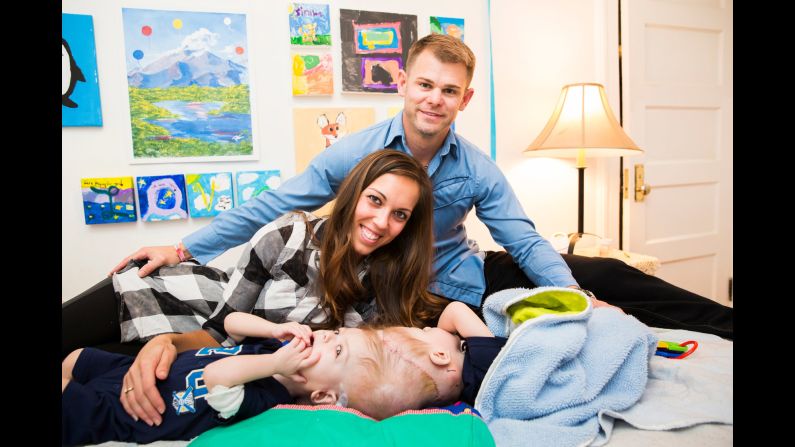Christian and Nicole pose on the bed with their twins. Anias is on the left, while Jadon is facing his father.