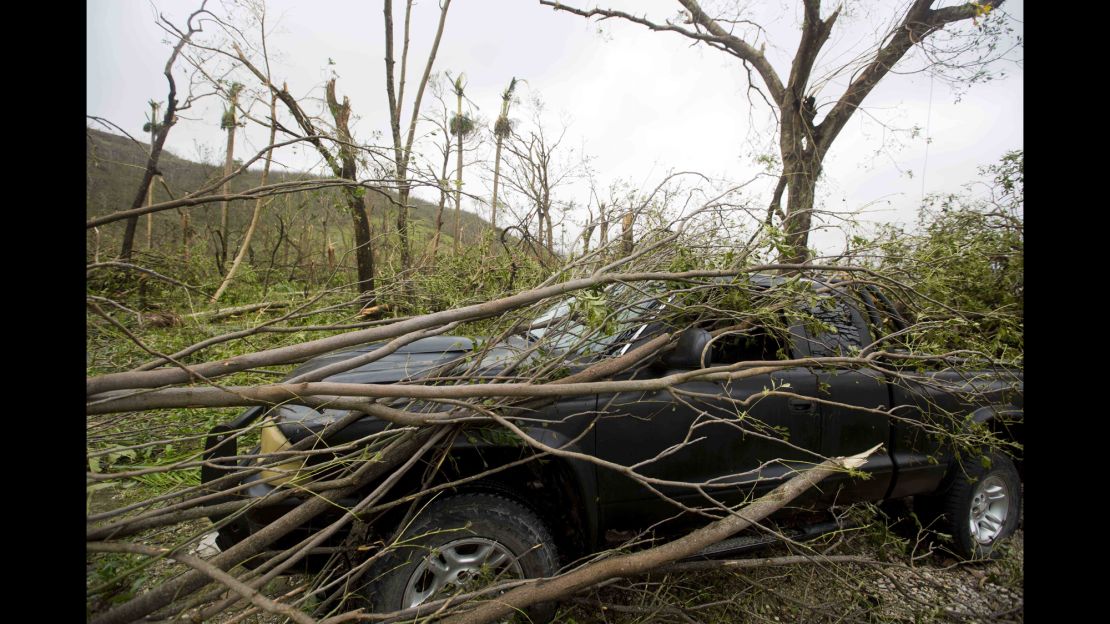 A vehicle sits covered in toppled tree limbs in Camp Perrin, a district of Les Cayes, Haiti.