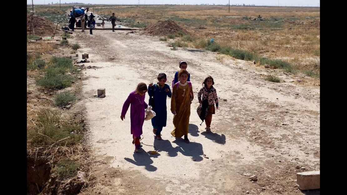 Amal (second from left) and her cousins approach the berm at the edge of Kurdish territory. In the background, others wait to be searched and called forward by Peshmerga.