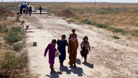 Amal (second from left) and her cousins approach the berm at the edge of Kurdish territory. In the background, others wait to be searched and called forward by Peshmerga.