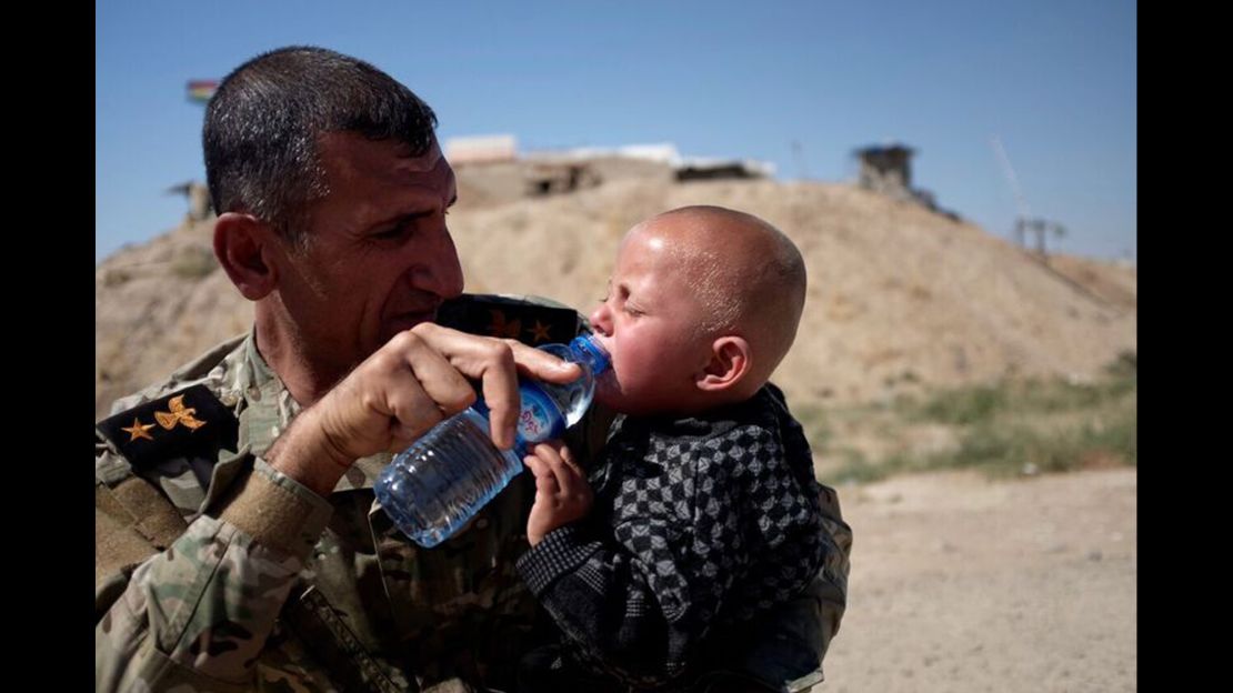 Peshmerga Commander Araz Abdal Rahman gives water to a child at Daqouq. 