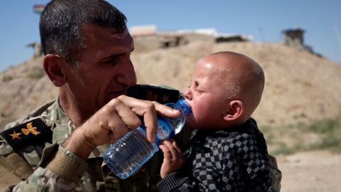 Peshmerga Commander Araz Abdal Rahman gives water to a child at Daqouq.