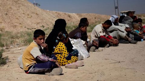 Families fleeing from their homes near the ISIS-controlled town of Hawija wait to be trucked away from the front line.