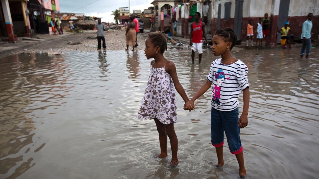 Girls wade through a flooded street in Les Cayes on Thursday, October 6.