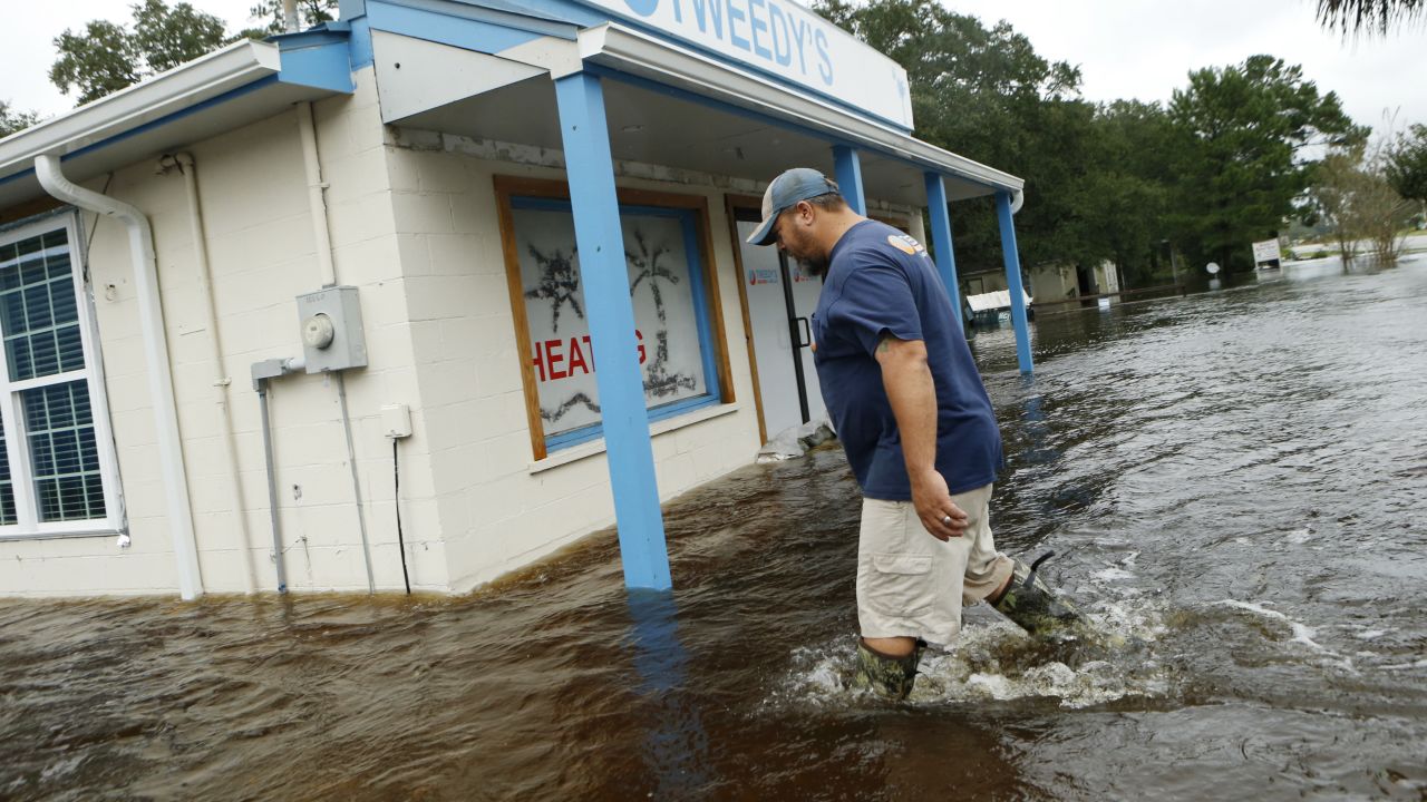 John Tweedy wades into the swift-moving floodwaters surrounding his business in McClellanville, South Carolina, on Saturday, October 8.