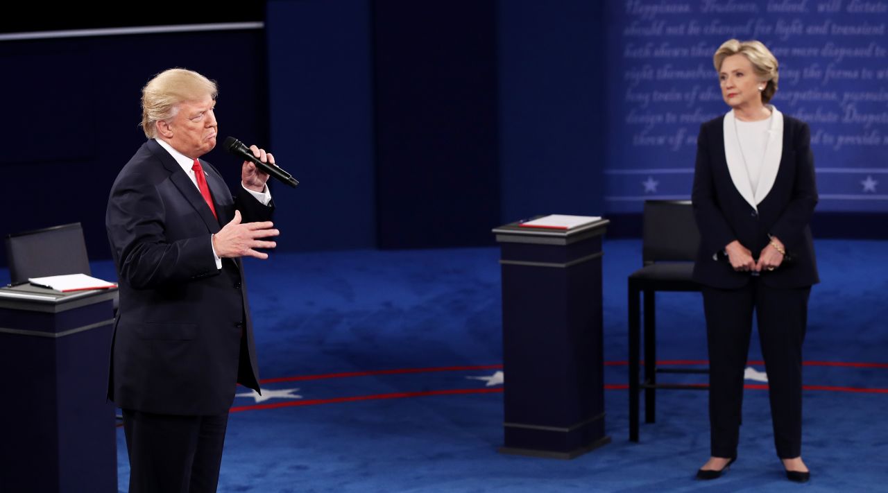 Clinton looks on as Trump speaks.