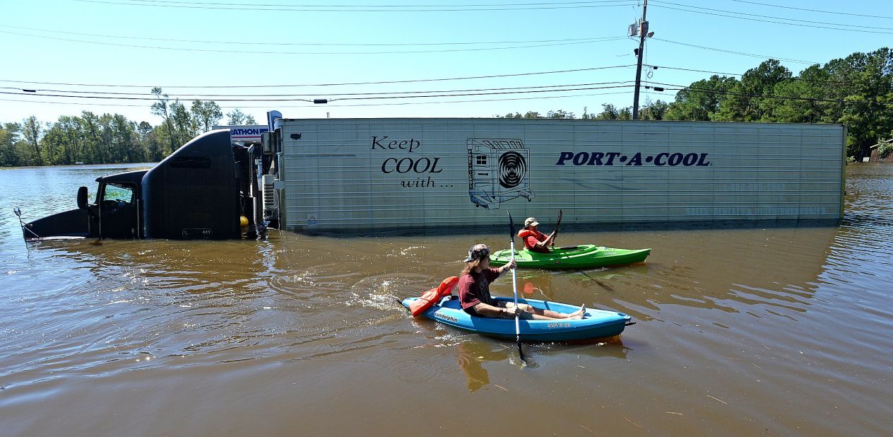 Anthony Writebol, left, and his cousin Melissa Hill paddle past a stranded tractor-trailer in Lumberton on October 9.