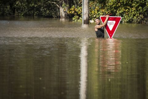 A man clings to a road sign after trying to swim out to help a stranded truck driver in Hope Mills, North Carolina, on October 9. Both were rescued.