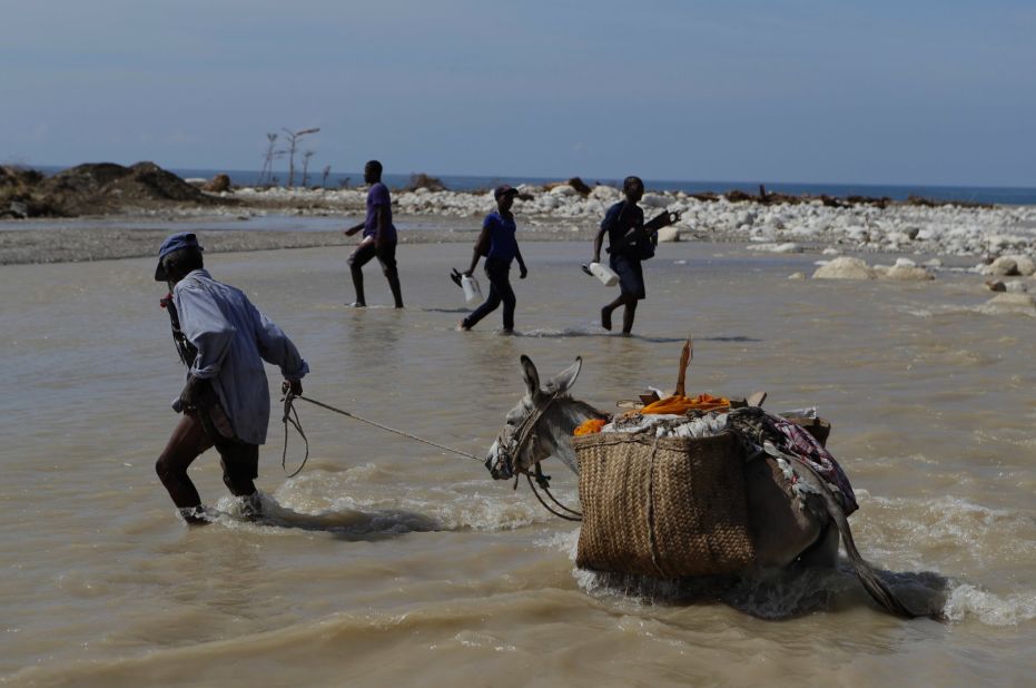 People cross one of the many southern coastal rivers where bridges were knocked out or damaged near Port-a-Piment on October 10. 