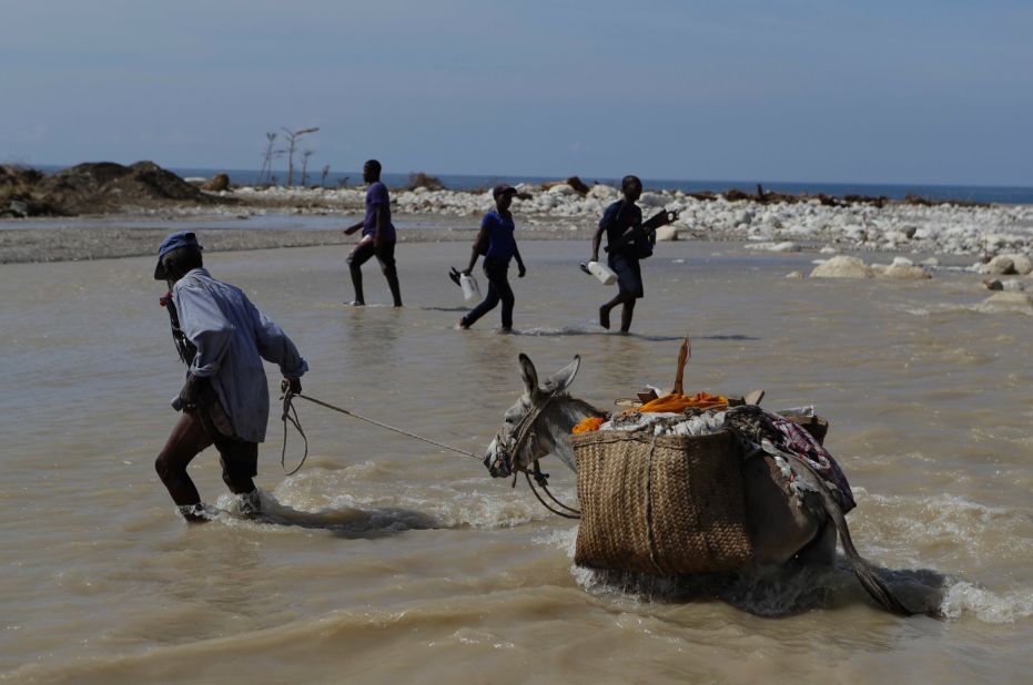 People cross one of the many southern coastal rivers where bridges were knocked out or damaged near Port-a-Piment on October 10.