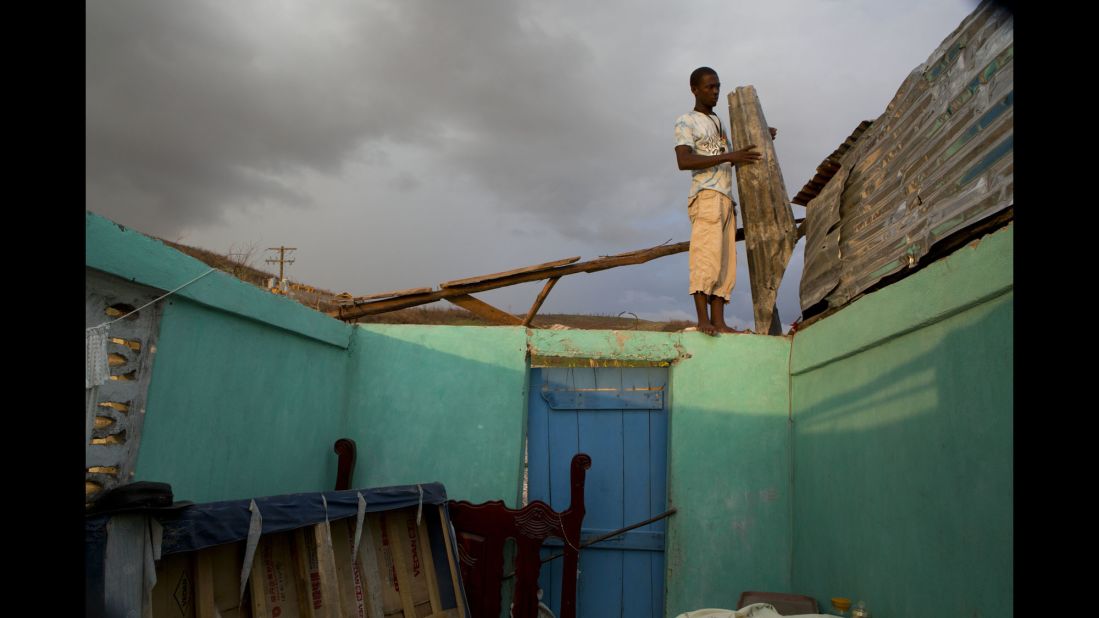 A man uses salvaged material to build a makeshift roof for his damaged house in Port-a-Piment on October 10.