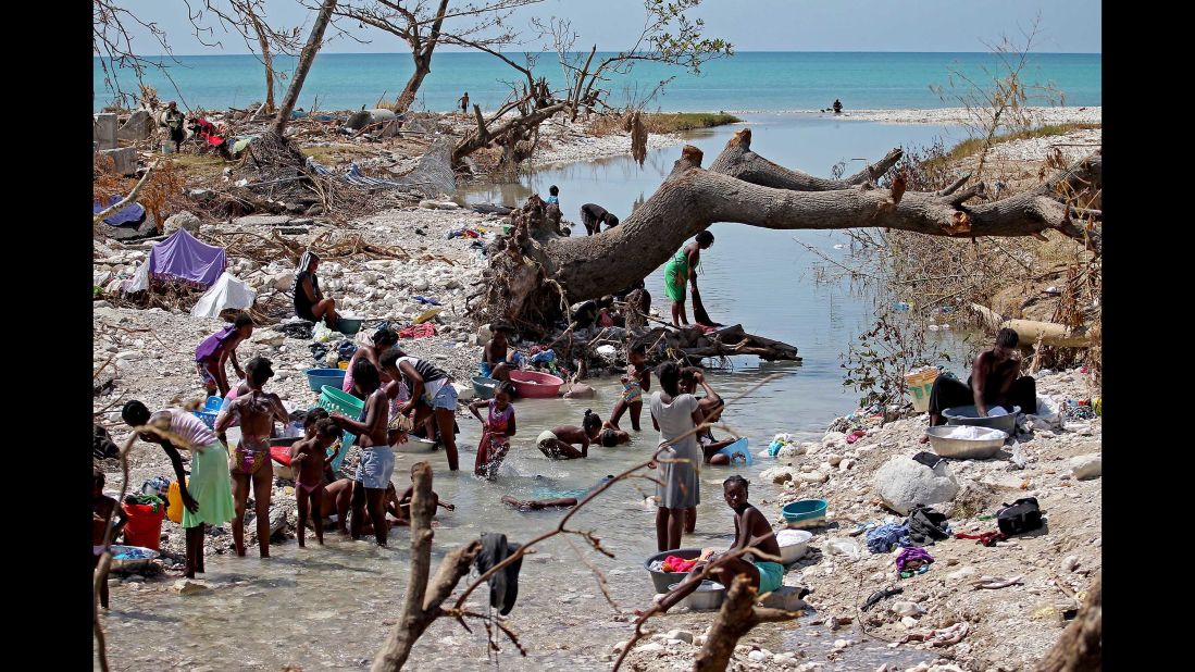 People bathe and wash clothes in a river that runs through Roche-à-Bateaux on October 9. Concerns are rising in the storm's aftermath about cholera, caused by the ingestion of contaminated water or food.