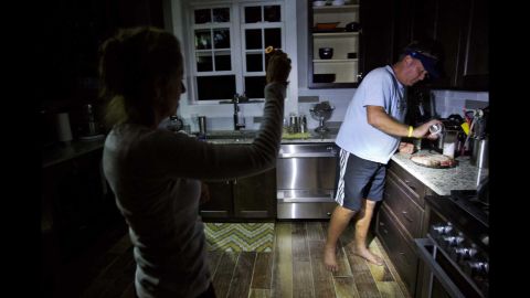 Without power in the hurricane's aftermath, Missy Zinc shines a light so her husband, Shawn, can prepare steaks to grill in Hilton Head, South Carolina, on Sunday, October 9.