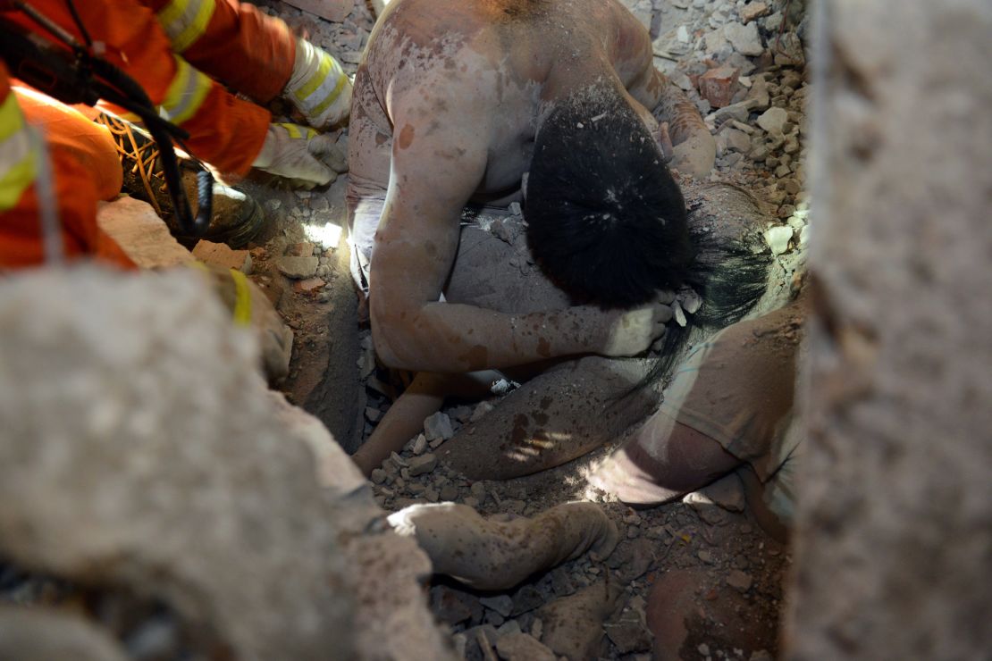 Rescuers try to save a young survivor who was protected by the body of her parents at an accident site after four buildings caved in during the early hours in Wenzhou in eastern China's Zhejiang province. 