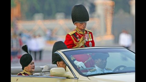 The King reviews an honor guard with Queen Sirikit and Crown Prince Vajiralongkorn during the annual military parade to celebrate his birthday in 2006.