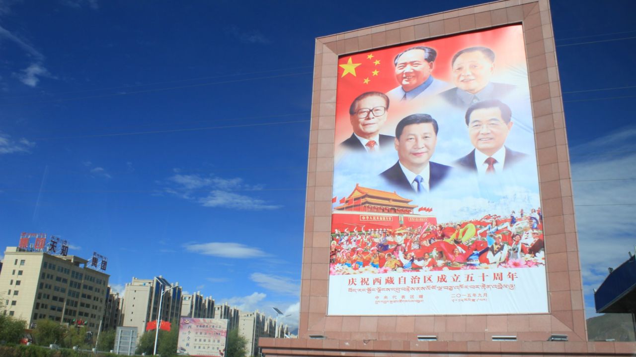 A poster featuring the headshots of the previous five leaders of China greets visitors outside Lhasa airport. This same grouping of photos is seen throughout Tibet.