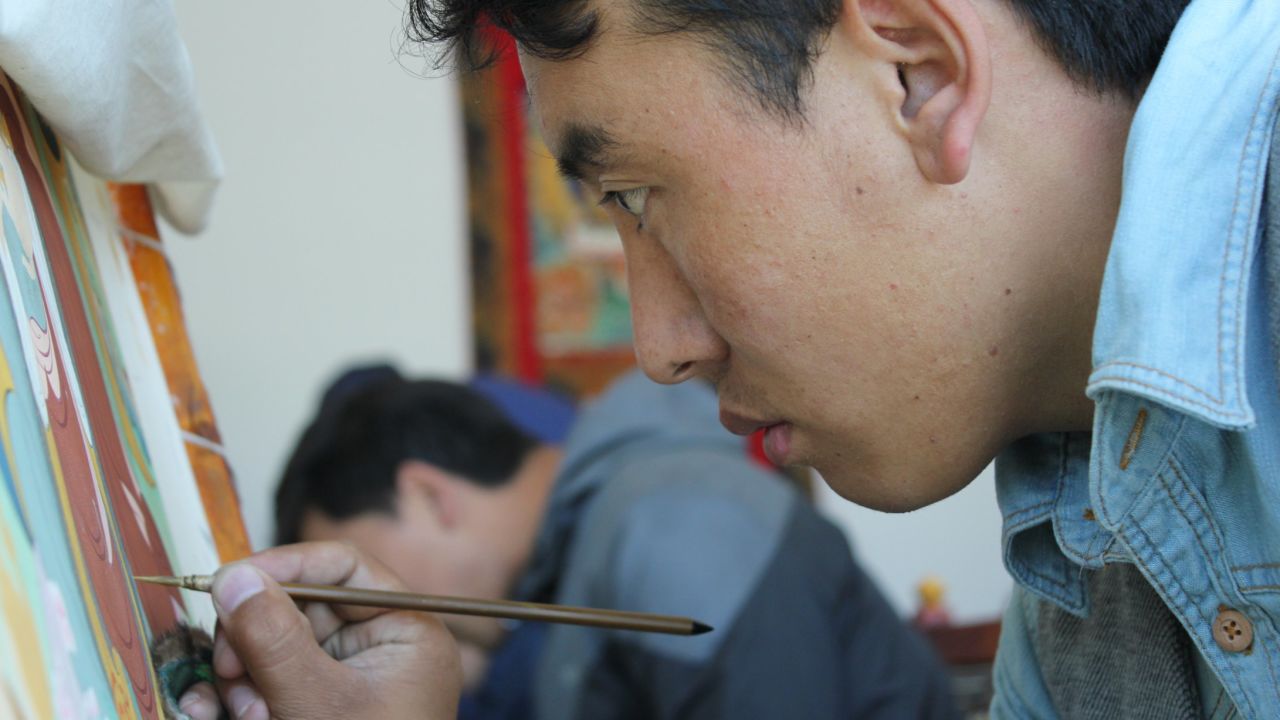 An art student paints a traditional thangka at an art school CNN was taken to on a government-approved tour.