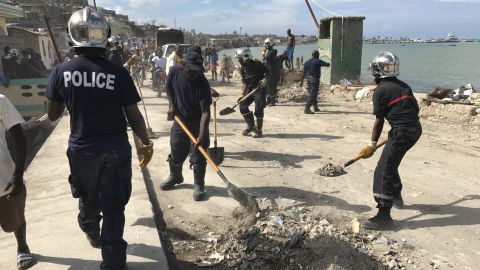 Local police work alongside volunteers cleaning up debris left by Hurricane Matthew along the waterfront in the town of Jeremie.
