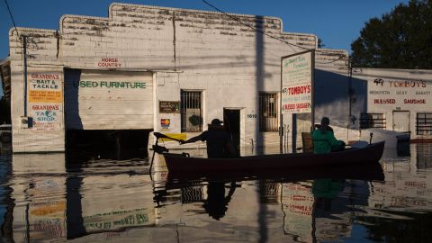 Ryan Christian and Delores Miller canoe down West 5th Street on Tuesday after checking on the home of Miller's elderly mother in downtown Lumberton.