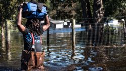 A man carries personal items through a flooded street caused by remnants of Hurricane Matthew on October 11, 2016 in Fair Bluff, North Carolina. Thousands of homes have been damaged in North Carolina as a result of the storm and many are still under threat of flooding.