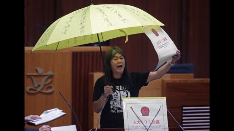 Leung Kwok-hung, holds a yellow umbrella and an oversized mock copy of the proposed anti-subversion legislation as she takes oath.